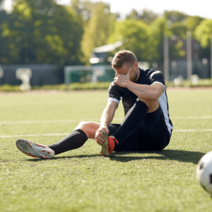 Un footballeur sur le terrain de football se tient le pied en raison d'une douleur de tendon